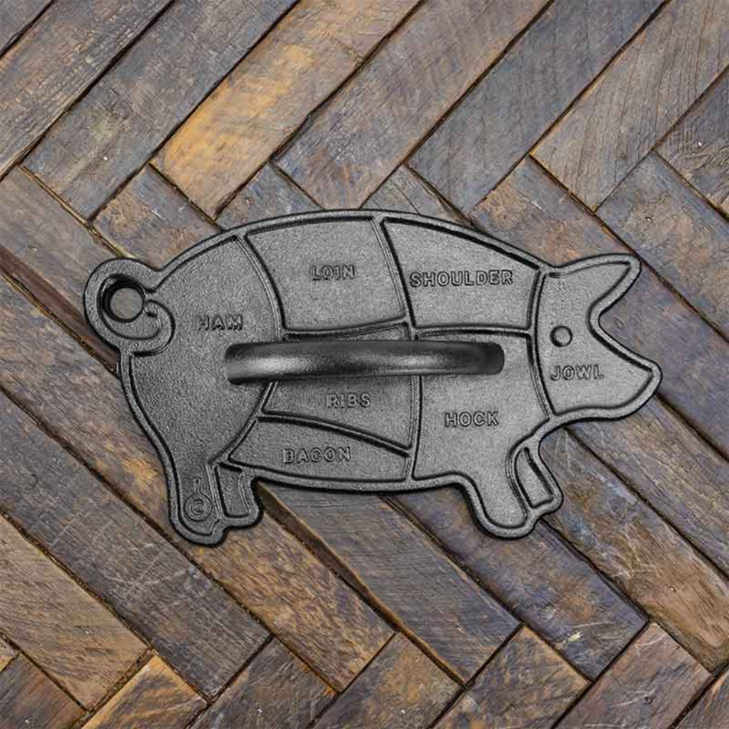 Cast iron pig-shaped meat cut diagram on a wooden surface